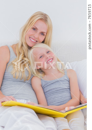 Mother holding a story book with her daughter Mother holding a story book with her daughter 7659715