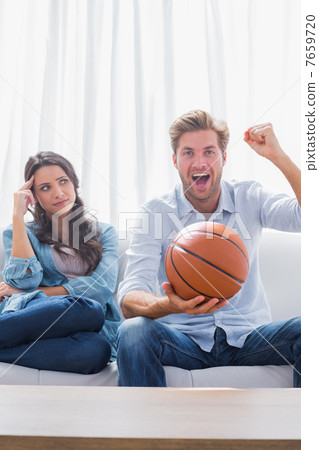 Woman looking at her husband cheering the basketball game 7659720