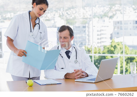 Doctor showing a folder to a colleague 7660262
