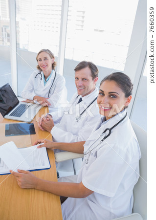 Overview of doctors working and looking at camera Overview of doctors working and looking at camera 7660359