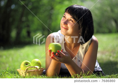 Young woman with apples lying on grass 7686860