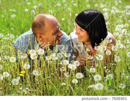 Young couple lying on grass in the field of dandelion Young couple lying on grass in the field of dandelion 7686861