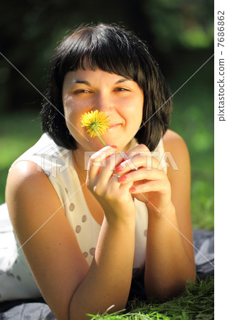 Young woman lying on grass with dandelion Young woman lying on grass with dandelion 7686862