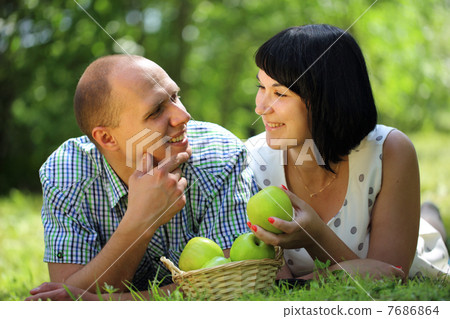 Young couple with apples lying on grass Young couple with apples lying on grass 7686864