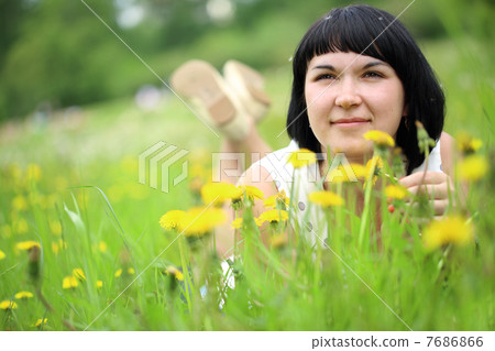 Young woman lying on grass in the field of dandelion 7686866