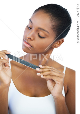 Serious woman looking at her nail file Serious woman looking at her nail file 7699185