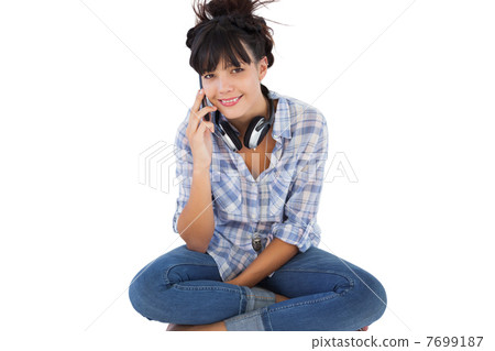 Young woman sitting on the floor with headphones calling someone 7699187