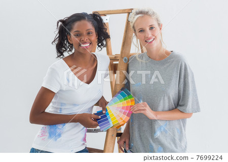 Friendly housemates choosing colour for wall looking at camera Friendly housemates choosing colour for wall looking at camera 7699224