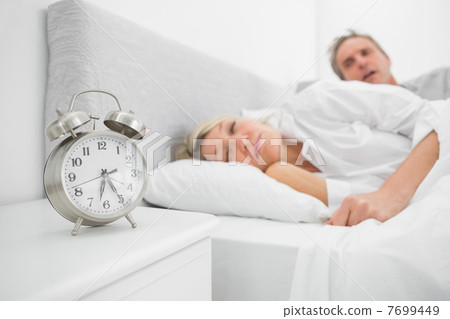 Man looking at ringing alarm clock Man looking at ringing alarm clock 7699449