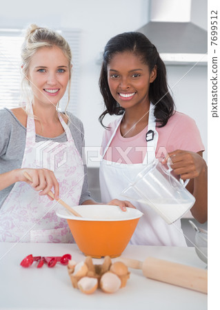 Smiling friends making dough together looking at camera Smiling friends making dough together looking at camera 7699512