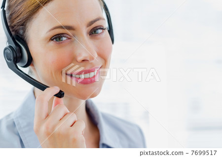 Call centre operator wearing headset smiling at camera Call centre operator wearing headset smiling at camera 7699517