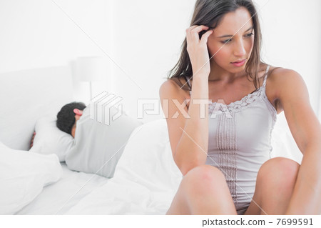 Uneasy woman sitting in bed 7699591