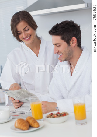 Happy man reading a newspaper while having breakfast Happy man reading a newspaper while having breakfast 7699637