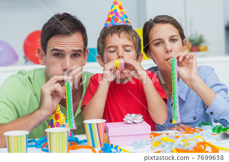 Beautiful family playing with party horns Beautiful family playing with party horns 7699638