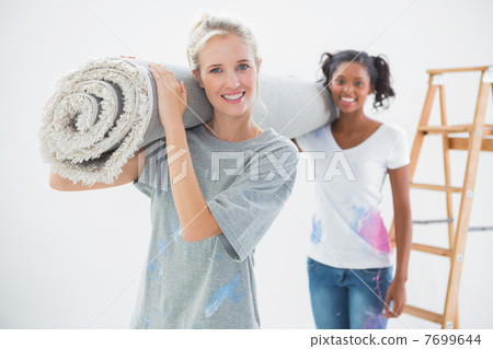 Smiling housemates carrying rolled up rug Smiling housemates carrying rolled up rug 7699644