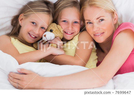 Woman napping in bed with her cute children Woman napping in bed with her cute children 7699647