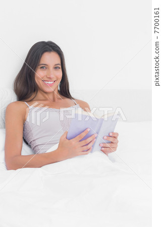 Portrait of a woman reading a lilac book in bed 7700161