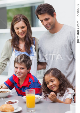 Parents looking at their children having breakfast Parents looking at their children having breakfast 7700207