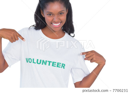 Smiling young woman wearing volunteer tshirt and pointing to it 7700231