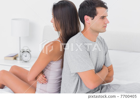 Couple sulking each other sitting back to back on bed Couple sulking each other sitting back to back on bed 7700405