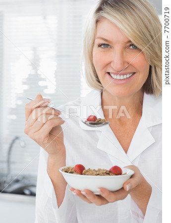 Smiling woman having cereal for breakfast Smiling woman having cereal for breakfast 7700719