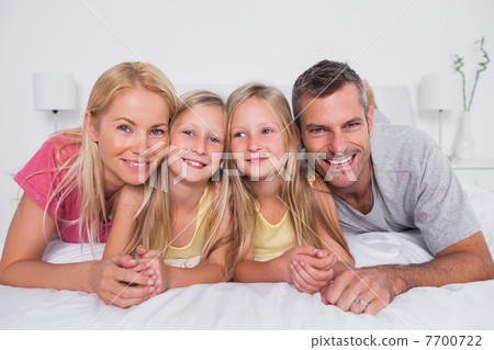 Portrait of parents lying in bed with their children 7700722