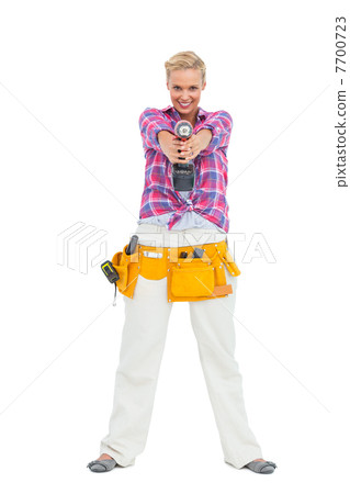 Blonde standing while pointing a drill at camera Blonde standing while pointing a drill at camera 7700723