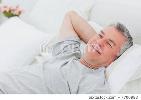 Smiling man relaxing in bed 7700988