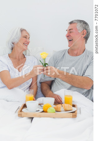 Mature man giving wife a yellow rose 7701072