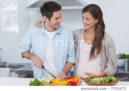 Man chopping vegetables next to his pregnant partner 7701073