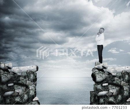 Businessman thinking at the edge of a cliff 7701233