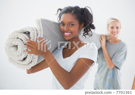 Happy housemates carrying rolled up rug Happy housemates carrying rolled up rug 7701361