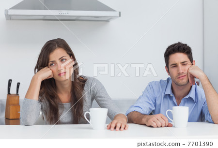 Tired couple sitting at the table with a cup of coffee Tired couple sitting at the table with a cup of coffee 7701390
