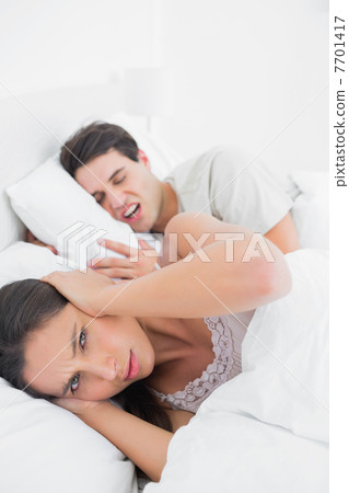 Pretty woman covering ears while her partner is snoring Pretty woman covering ears while her partner is snoring 7701417
