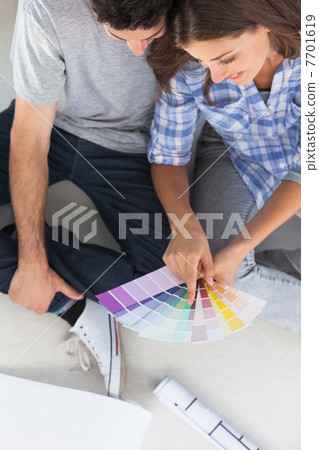 Woman pointing at color charts sitting in her new house Woman pointing at color charts sitting in her new house 7701619