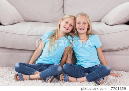 Twins sitting on a carpet 7701859