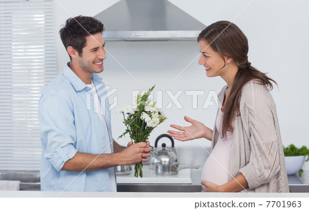 Man giving flowers to his pregnant partner 7701963