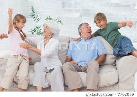 Grandchildren jumping on couch with their grandparents Grandchildren jumping on couch with their grandparents 7702099