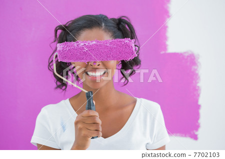 Pretty woman holding paintroller over her face Pretty woman holding paintroller over her face 7702103