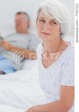 Anxious mature woman sitting in bed Anxious mature woman sitting in bed 7702322