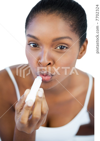 Young woman putting lip balm on her lips Young woman putting lip balm on her lips 7702324