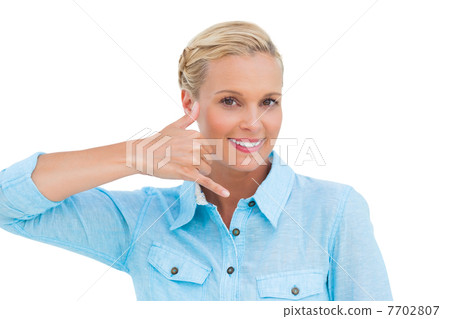 Smiling blonde looking at camera and doing a symbol of phone wit Smiling blonde looking at camera and doing a symbol of phone wit 7702807