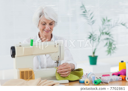 Retired woman using the sewing machine Retired woman using the sewing machine 7702861