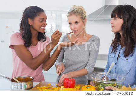 Cheerful friends preparing a meal together Cheerful friends preparing a meal together 7703018