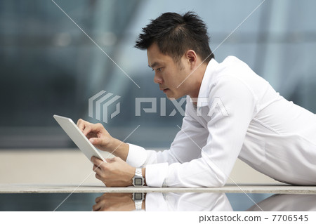 Asian Business man using a Digital Tablet Asian Business man using a Digital Tablet 7706545