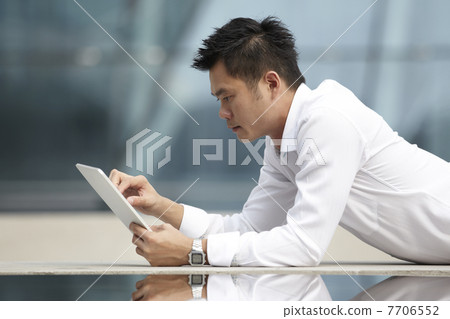 Asian Business man using a Digital Tablet Asian Business man using a Digital Tablet 7706552