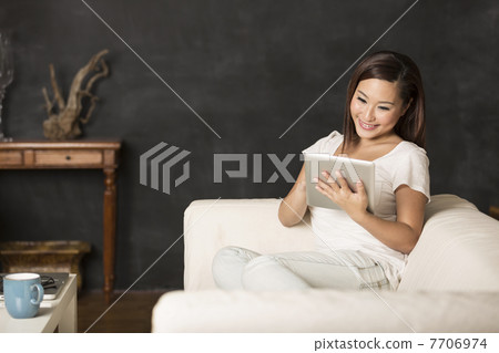 Chinese woman sitting on sofa using Digital Tablet Chinese woman sitting on sofa using Digital Tablet 7706974