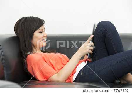 Young Chinese woman at home using a Digital Tablet Young Chinese woman at home using a Digital Tablet 7707192