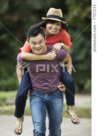 Portrait of a Chinese man giving a piggyback to his girlfriend 7707235