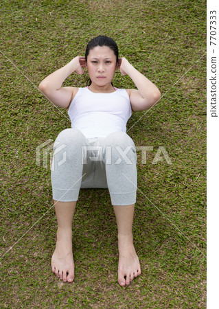 Chinese woman doing situps in park. 7707333